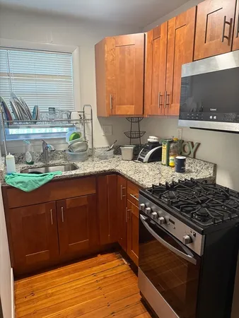 a kitchen with granite countertop wooden cabinets and a stove top oven