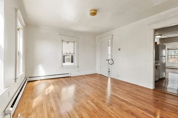 an empty room with wooden floor and windows
