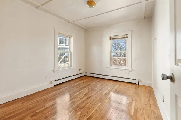 an empty room with wooden floor and windows