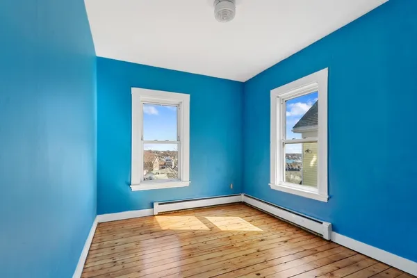 a view of an empty room with window and wooden floor