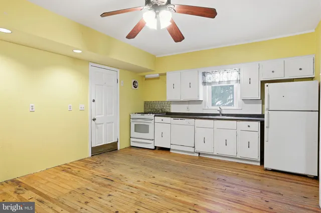 a kitchen with granite countertop white cabinets and white appliances