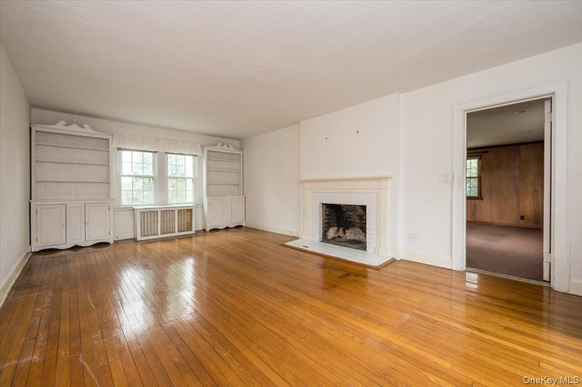 1 Edna Place New Rochelle, NY 10804 - Photo 3 of 24 an empty room with wooden floor fireplace and windows