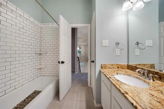 a bathroom with a granite countertop sink a bathtub and shower