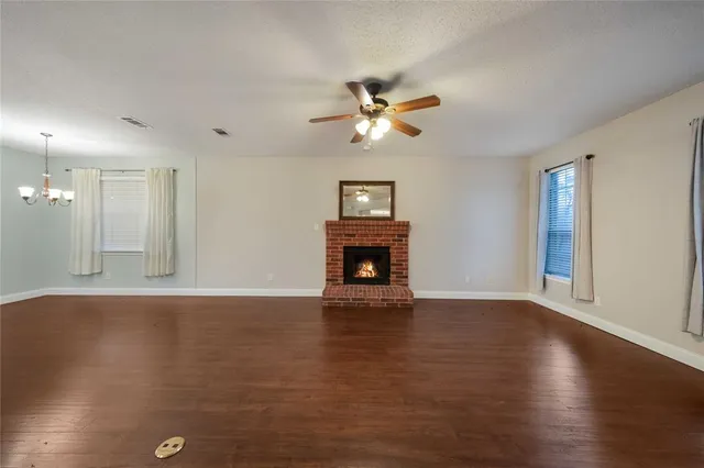 a view of a livingroom with a fireplace a ceiling fan and a window