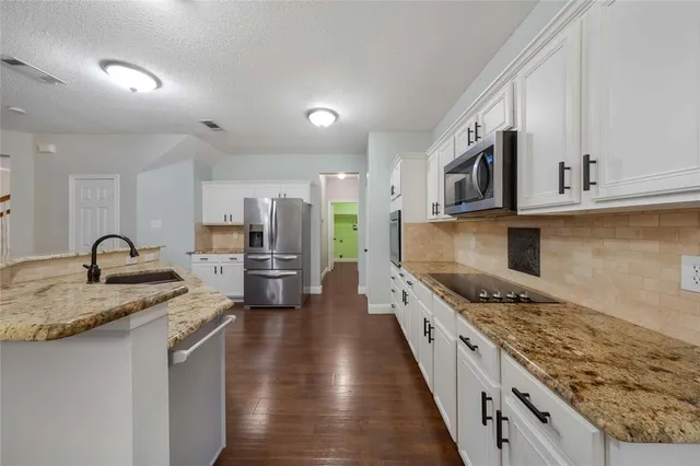a kitchen with stainless steel appliances granite countertop a stove a sink and a microwave
