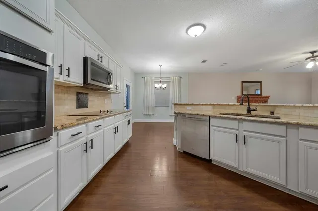 a large white kitchen with stainless steel appliances granite countertop lots of white cabinets a sink and dishwasher