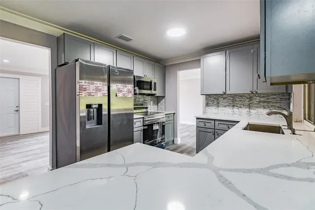 a kitchen with stainless steel appliances kitchen island granite countertop a refrigerator sink and cabinets