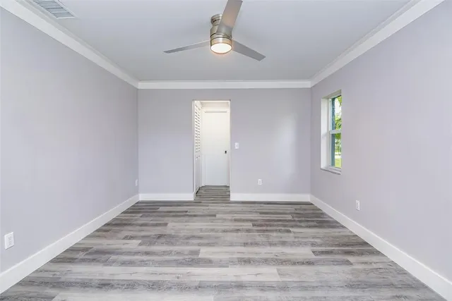 a view of an empty room with window and wooden floor