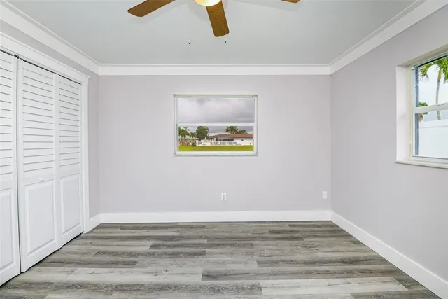 a view of an empty room with window and wooden floor