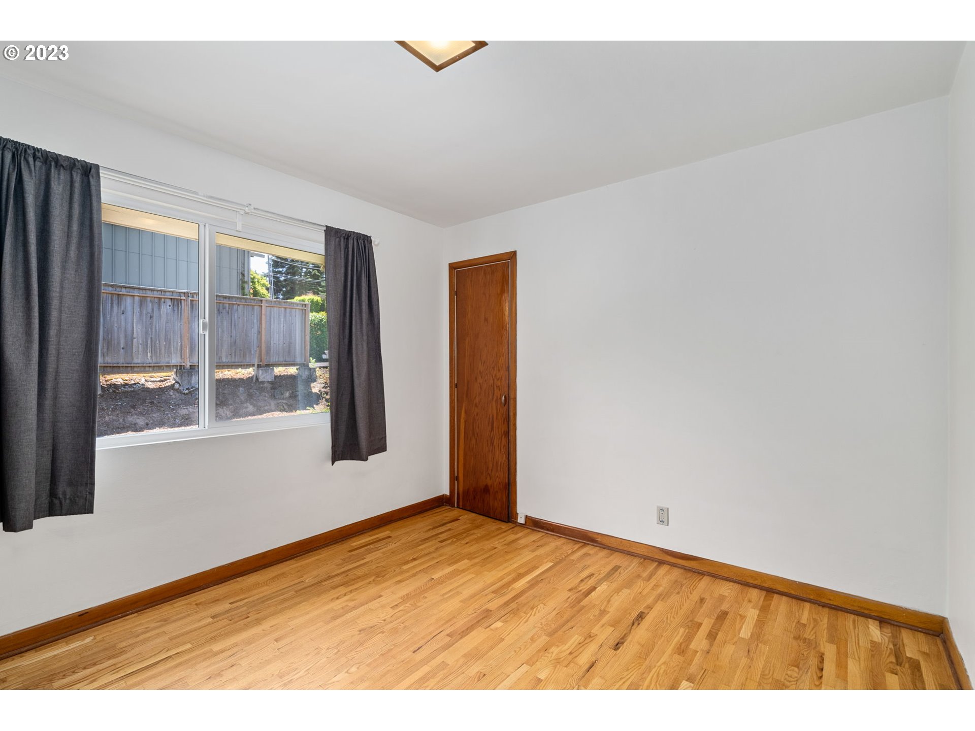 12050 Southwest 29th Avenue Portland, OR 97219 - Photo 19 of 36 a view of an empty room with wooden floor and a window