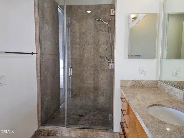 a bathroom with a granite countertop shower a mirror and a sink