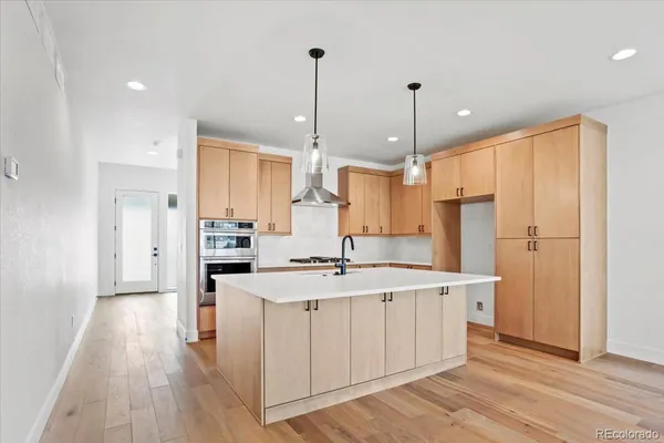 a view of a big room with wooden floor and a kitchen