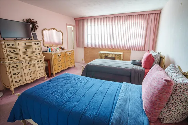 a bedroom with a bed a flat screen tv and dresser
