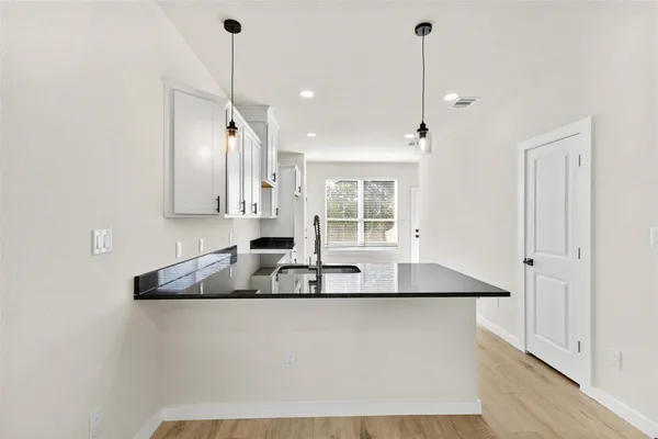 a kitchen with granite countertop white cabinets and window