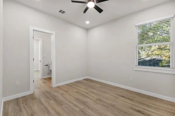 an empty room with wooden floor cabinet and windows