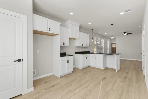 a open kitchen with white cabinets and wooden floor