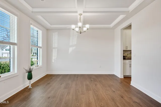 an empty room with wooden floor chandelier fan and windows