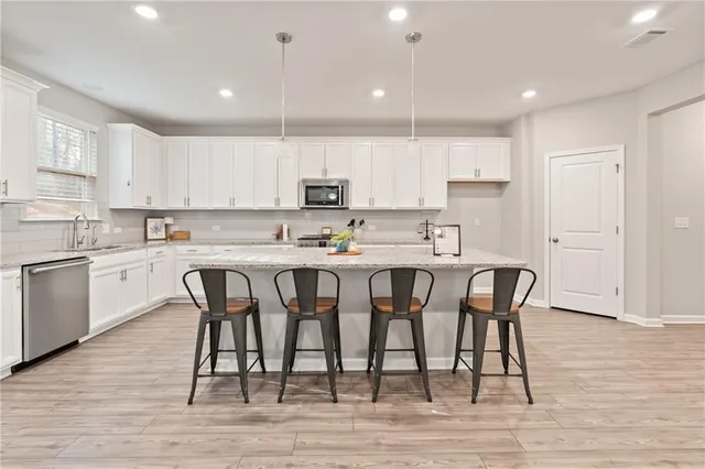 a kitchen with stainless steel appliances granite countertop a table chairs refrigerator sink and cabinets