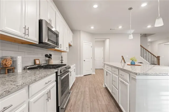 a kitchen with stainless steel appliances granite countertop a stove a sink and a refrigerator