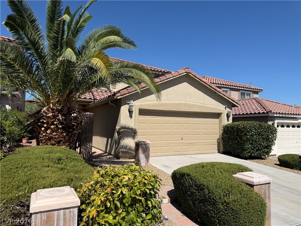 This charming residence features an attached garage and beautiful landscaping under a clear sky.