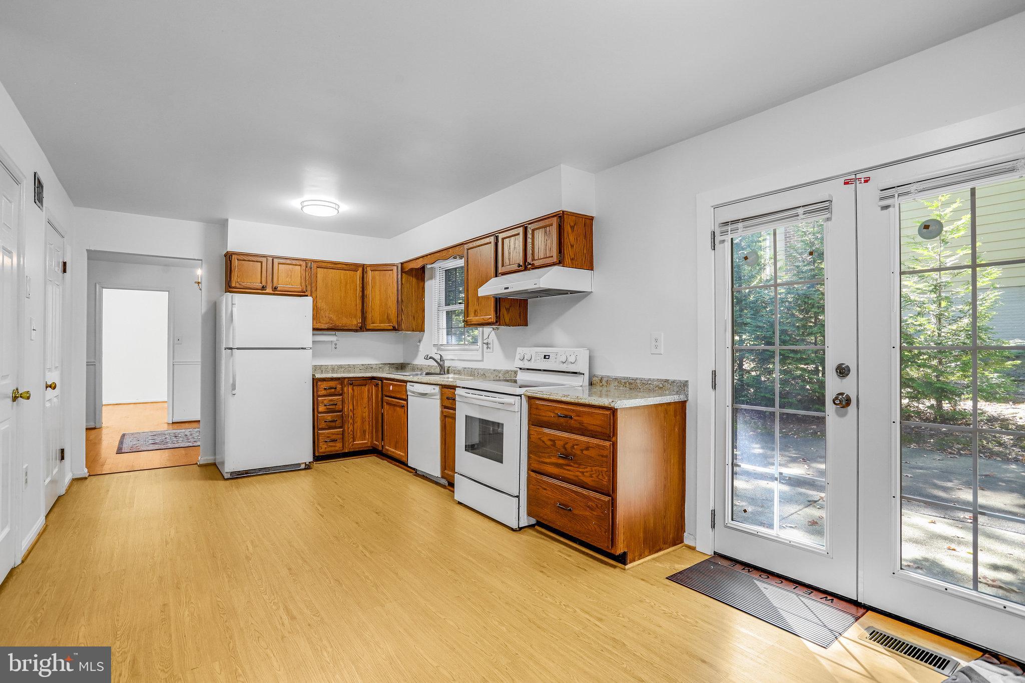 6935 Pineway Hyattsville, MD 20782 - Photo 5 of 14 a kitchen with stainless steel appliances granite countertop a stove a sink dishwasher a refrigerator and white cabinets with wooden floor
