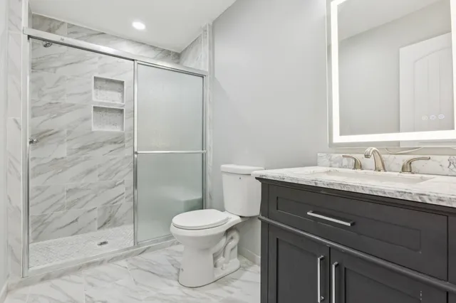 a bathroom with a granite countertop sink toilet and shower