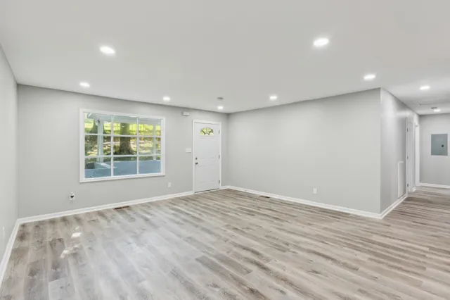 an empty room with wooden floor and windows