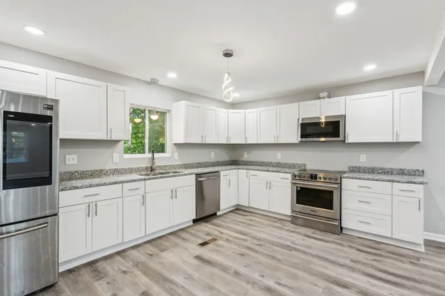 a kitchen with granite countertop cabinets stainless steel appliances and a sink