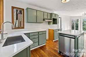 a kitchen with stainless steel appliances granite countertop a sink and a stove top oven with wooden floor