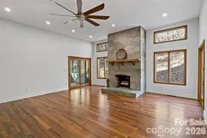 an empty room with windows fireplace and a ceiling fan