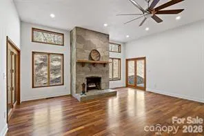 a view of an empty room with window and wooden floor