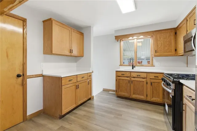 a kitchen with stainless steel appliances granite countertop a stove a sink and a refrigerator with wooden floor