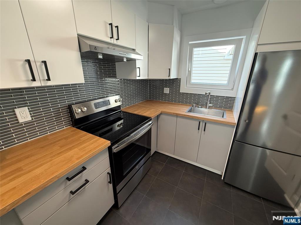 a kitchen that has a sink a stove and a refrigerator