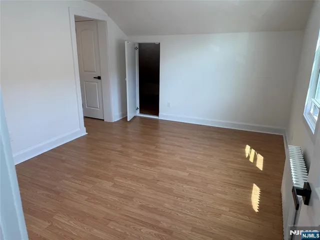 a view of an empty room with wooden floor and windows