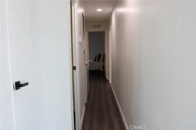 a view of a hallway with wooden floor and a bathroom