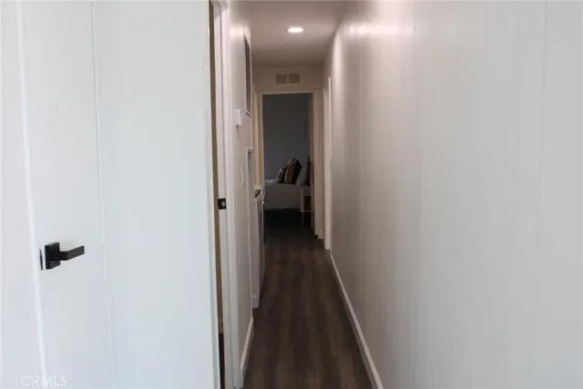 a view of a hallway with wooden floor and a bathroom