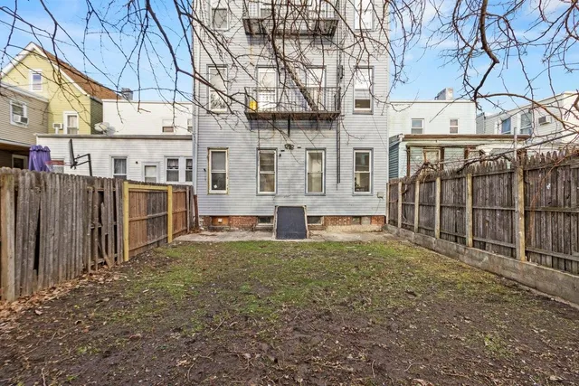 a view of a blue house with large trees and wooden fence