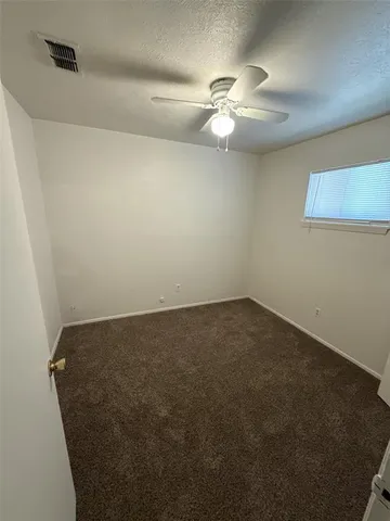 an empty room with a chandelier fan and a table