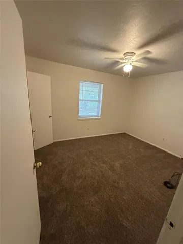 an empty room with a ceiling fan and a window