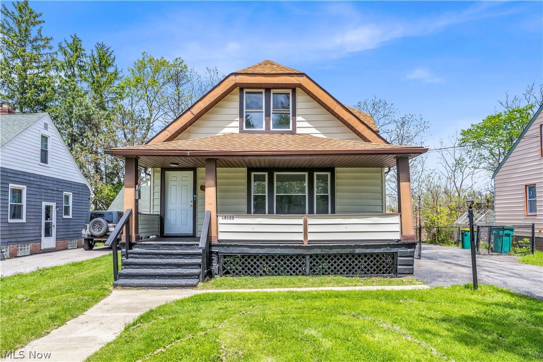 18123 McCracken Road Maple Heights, OH 44137 - Photo 1 of 27 Gable-roof property featuring light-colored siding with contrasting trim, a covered front porch with dark pillars and lattice skirting, and a concrete walkway leading to the entrance