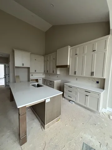 a kitchen that has a lot of white cabinets and stainless steel appliances