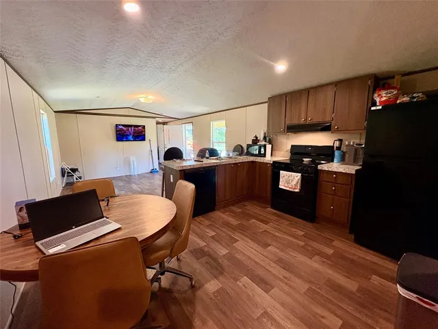 a living room with stainless steel appliances furniture a dining table and kitchen view