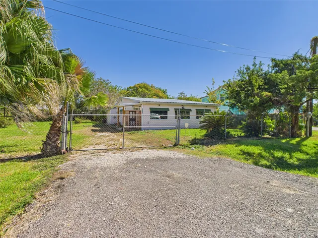 a view of a house with a small yard and a large tree