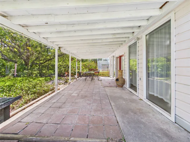 a view of a patio with table and chairs in front of it