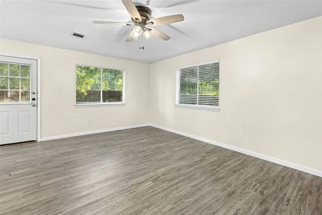 a view of an empty room with wooden floor and a window