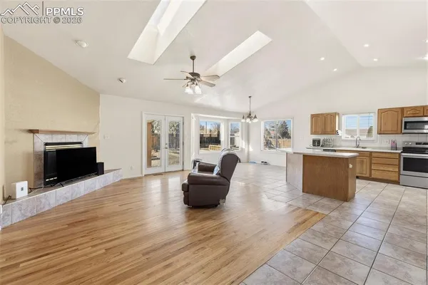 a large living room with stainless steel appliances kitchen island granite countertop a large kitchen island a stove a sink dishwasher and a fireplace with wooden floor