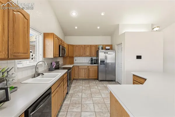 a large kitchen with a large counter top a sink stainless steel appliances and cabinets