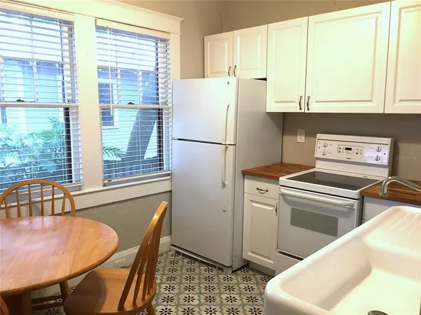 a kitchen with stainless steel appliances granite countertop a refrigerator a stove a sink and white cabinets with wooden floors