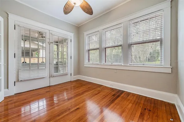 a view of an empty room with wooden floor and a window