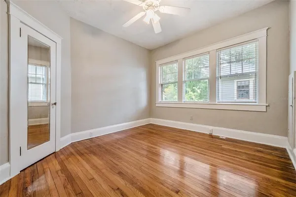 a view of an empty room with wooden floor and a window